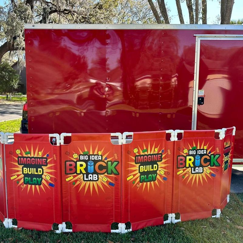 Brick Lab and Imagine Build Play panels set up on the grass in front of the red trailer