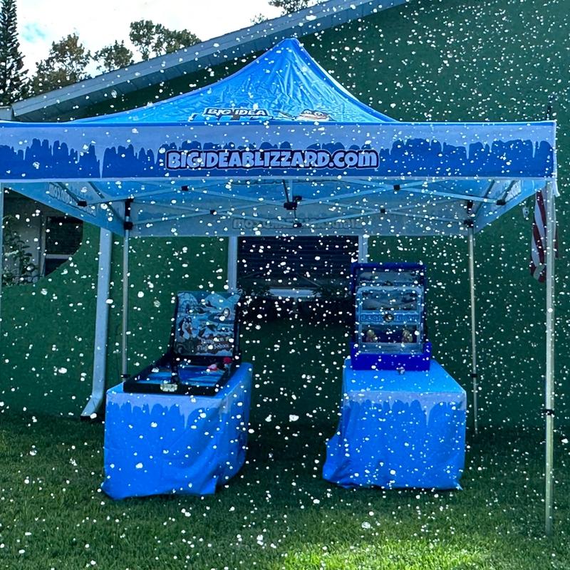 A Big Idea Blizzard tent over two covered game tables as snow falls on the lawn