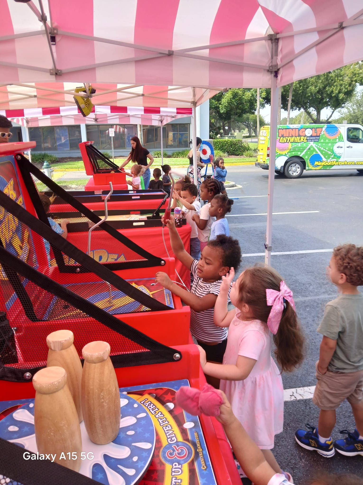Kids playing carnival games under a red and white striped tent at a carnival event in Atlanta