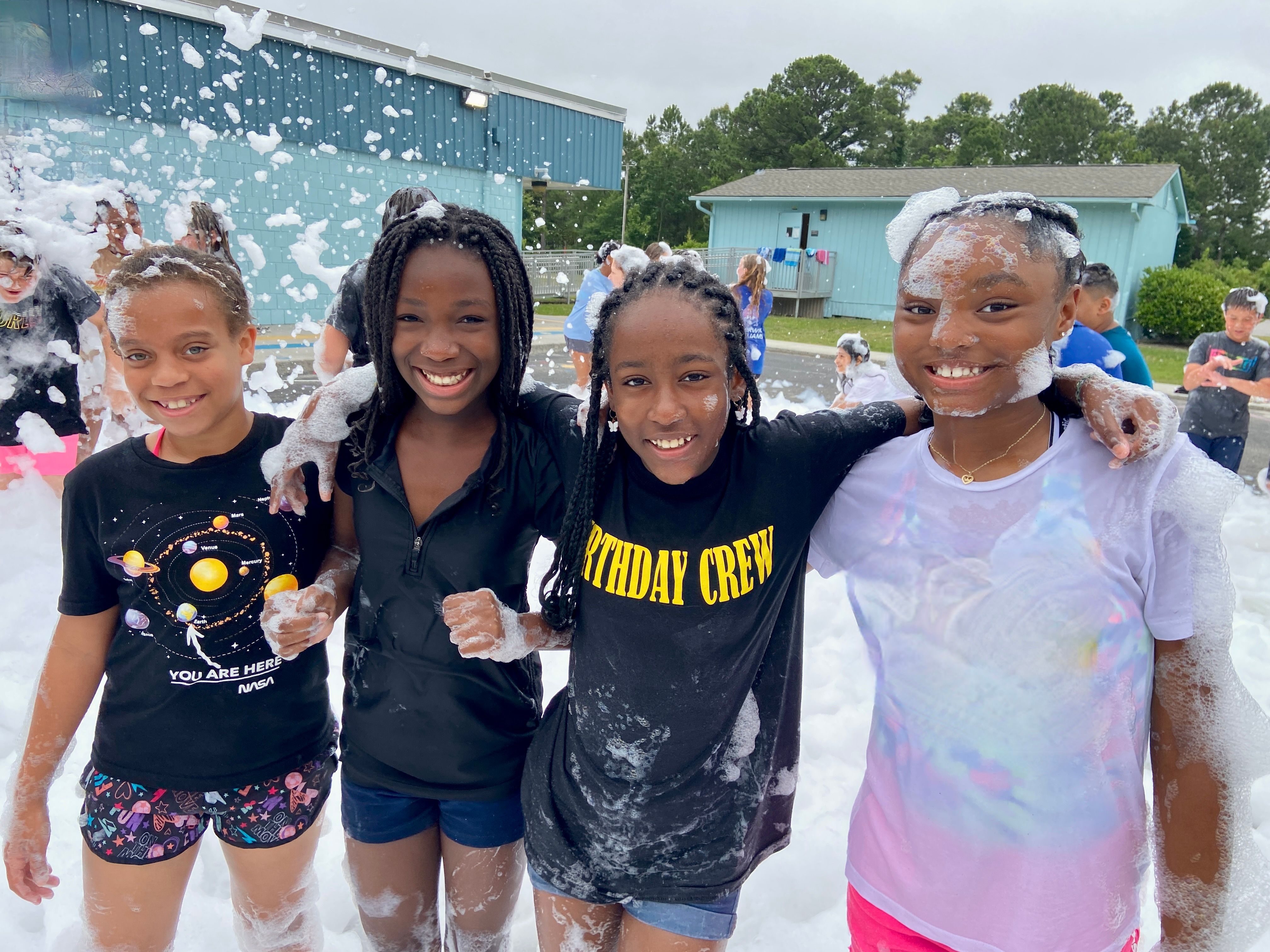 Several kids at field day, smiling at a foam party.