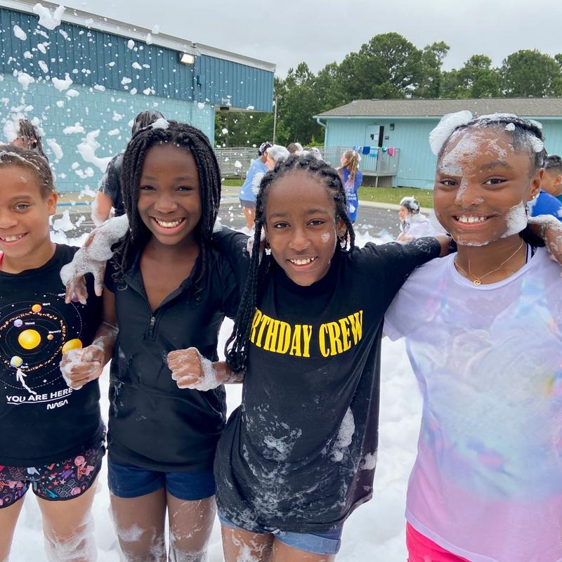 Several kids at field day, smiling at a foam party.