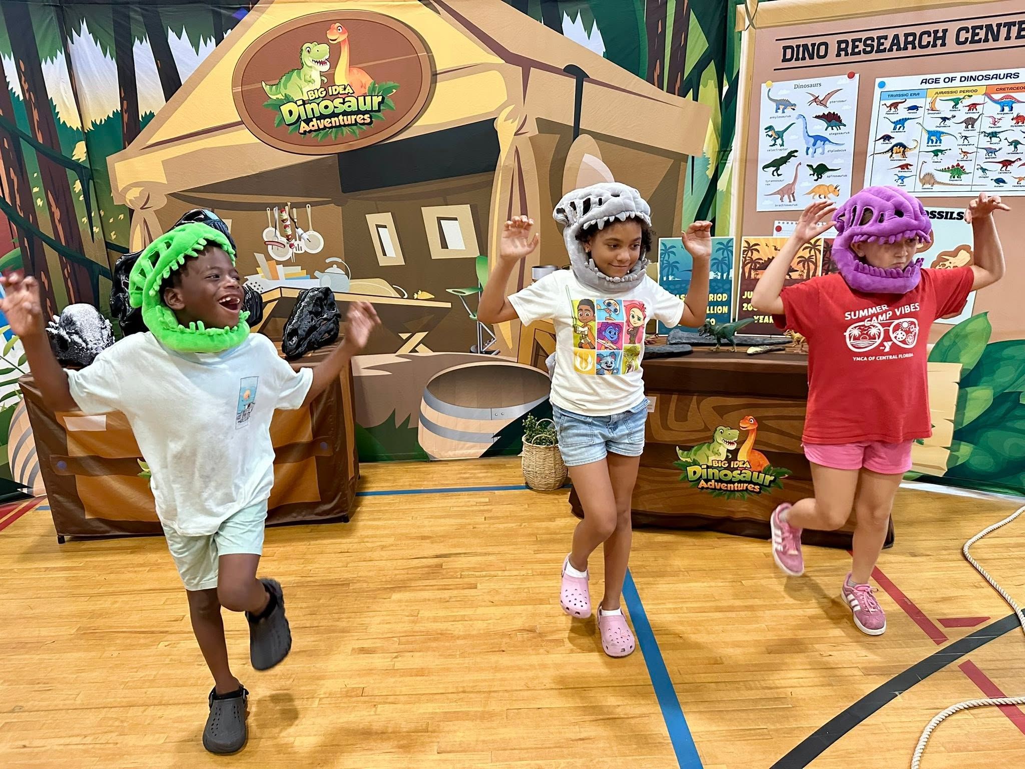 Kids in dinosaur hats run through the Dino Research Center