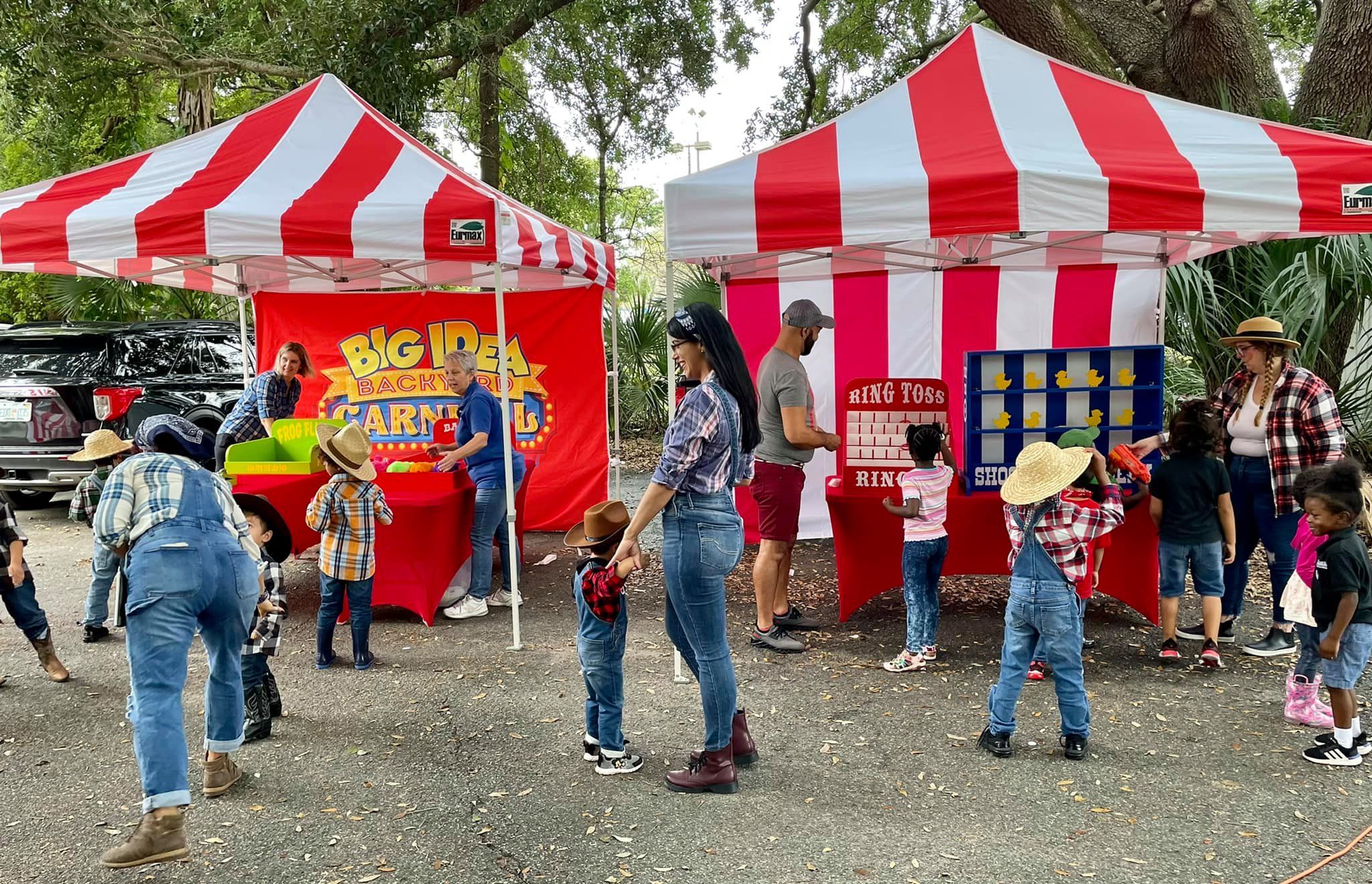 Two red and white striped tents with six classic carnival games setup at an event.