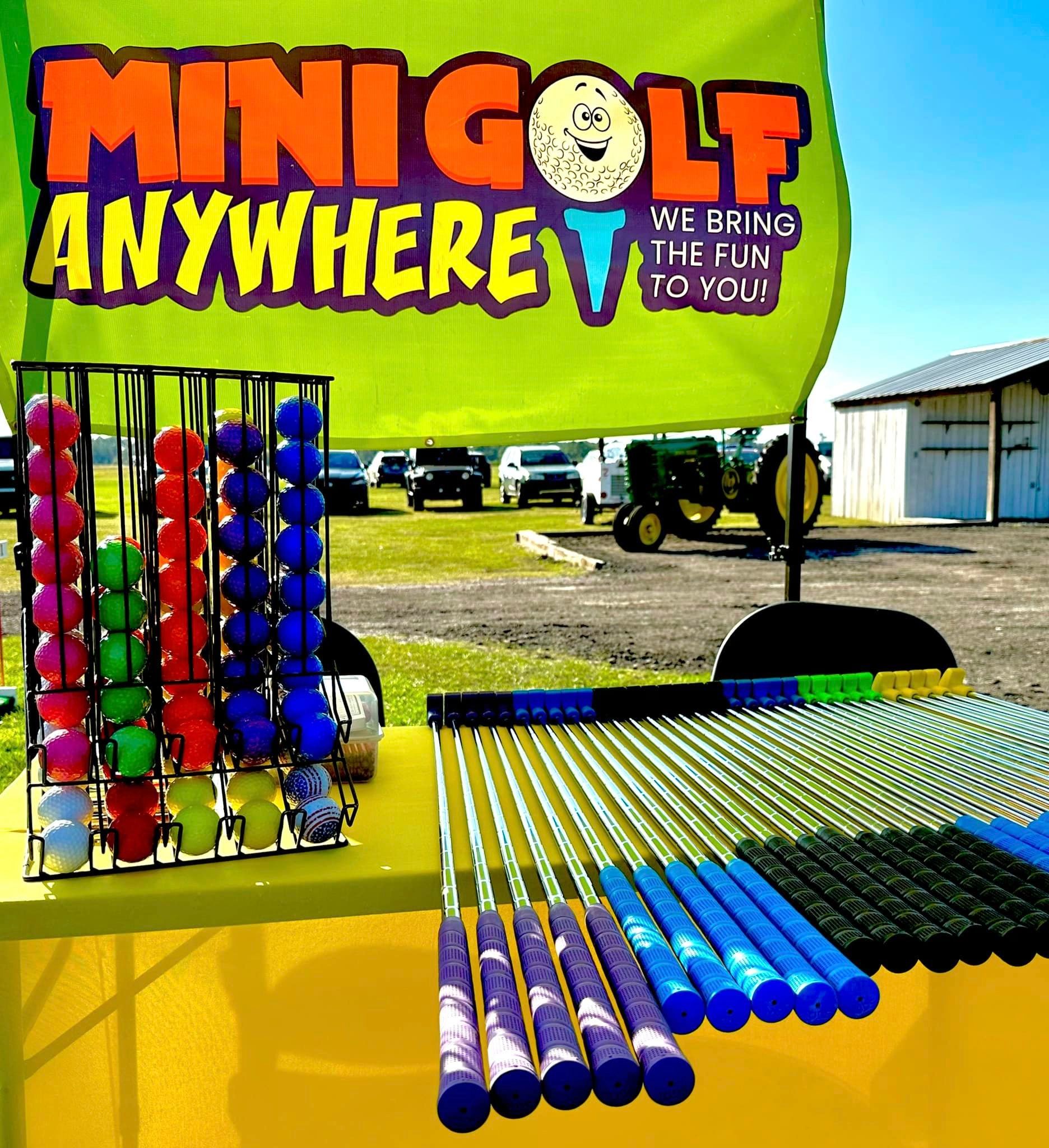 racks of colored putters and balls in front of a Mini Golf Anywhere banner