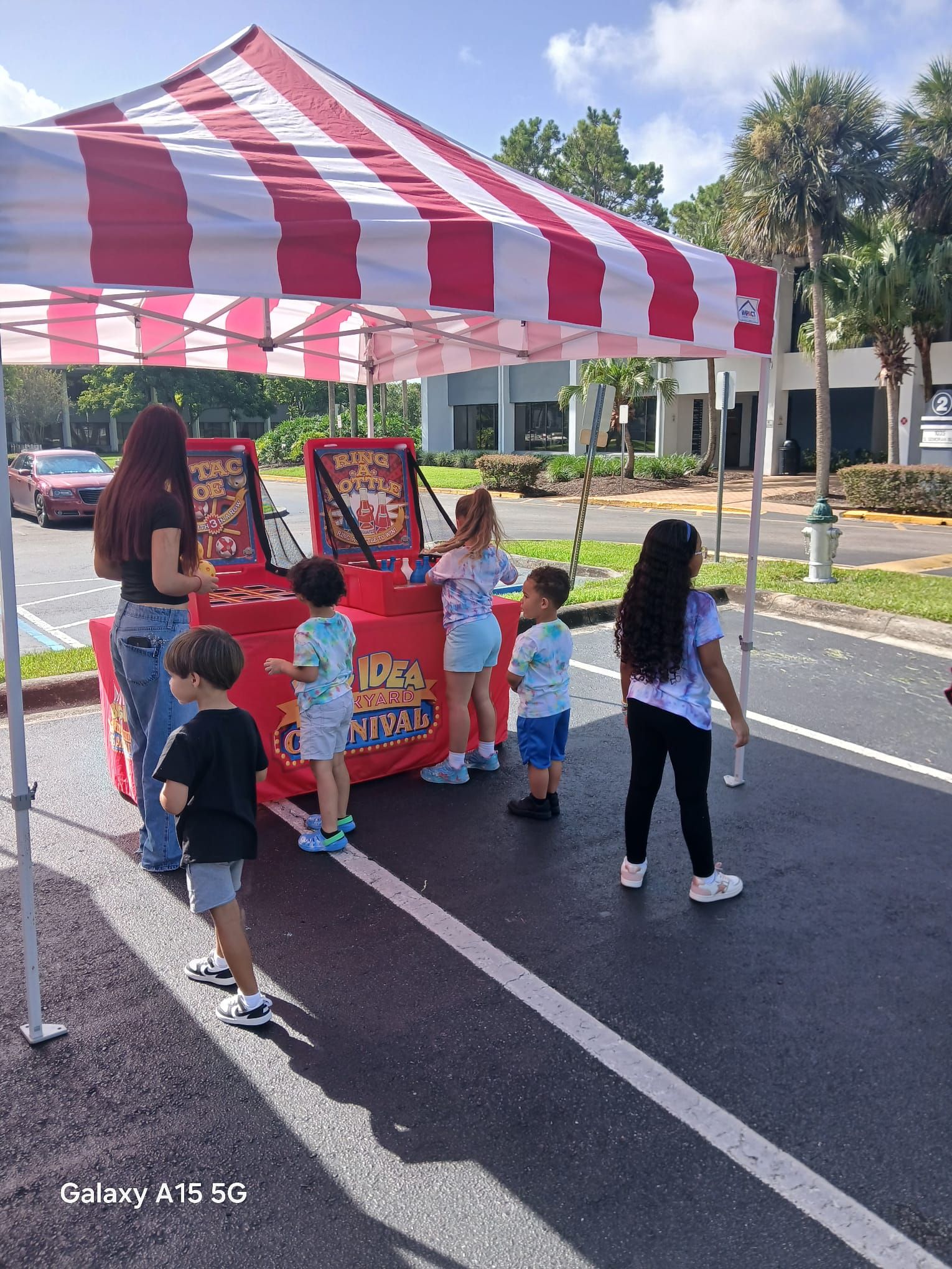 Kids playing carnival games under a red and white striped tent