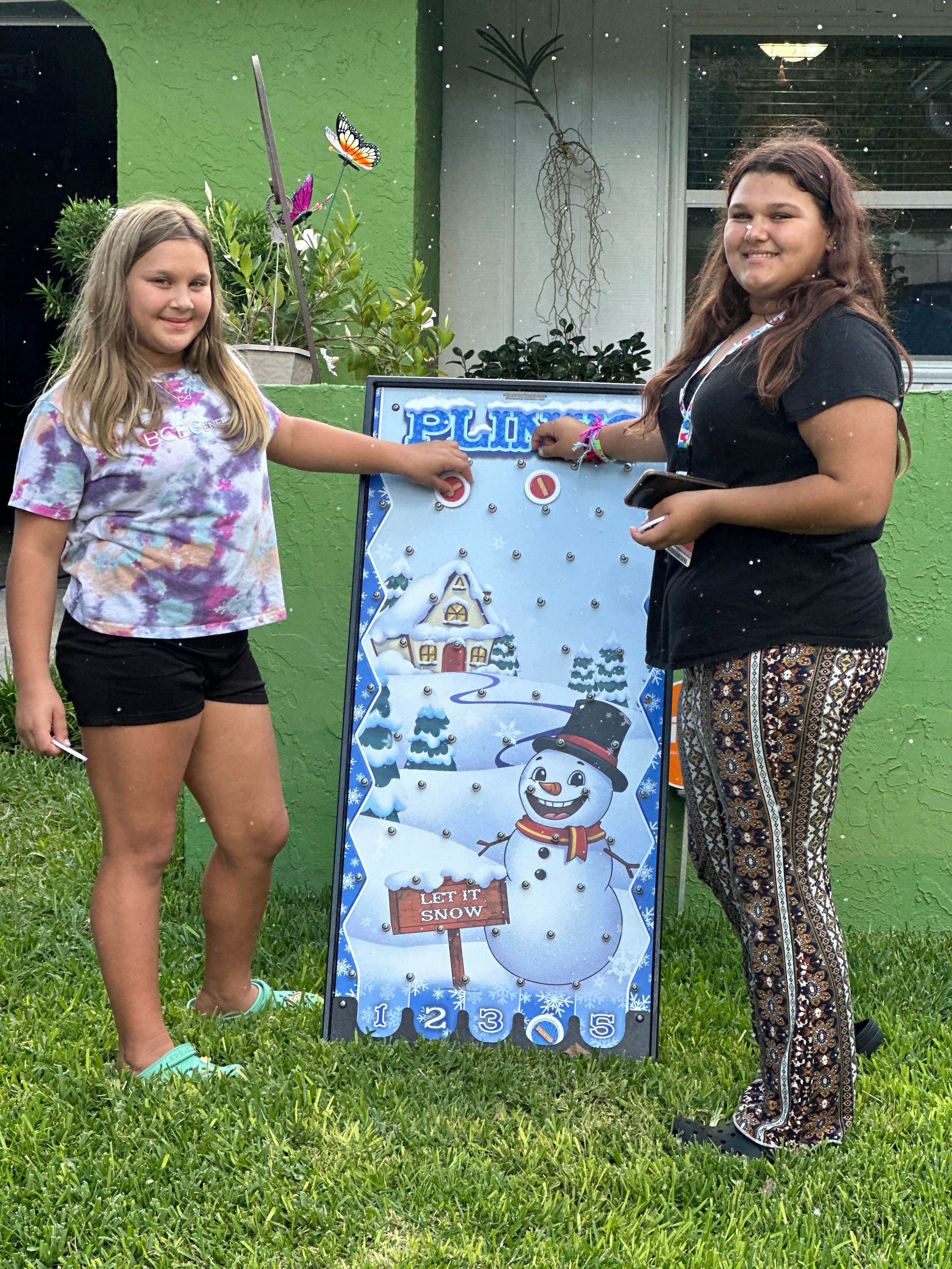 Two girls play the Let It Snow Plinko board