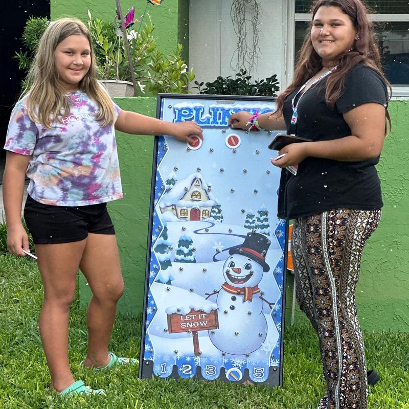 Two girls play the Let It Snow Plinko board
