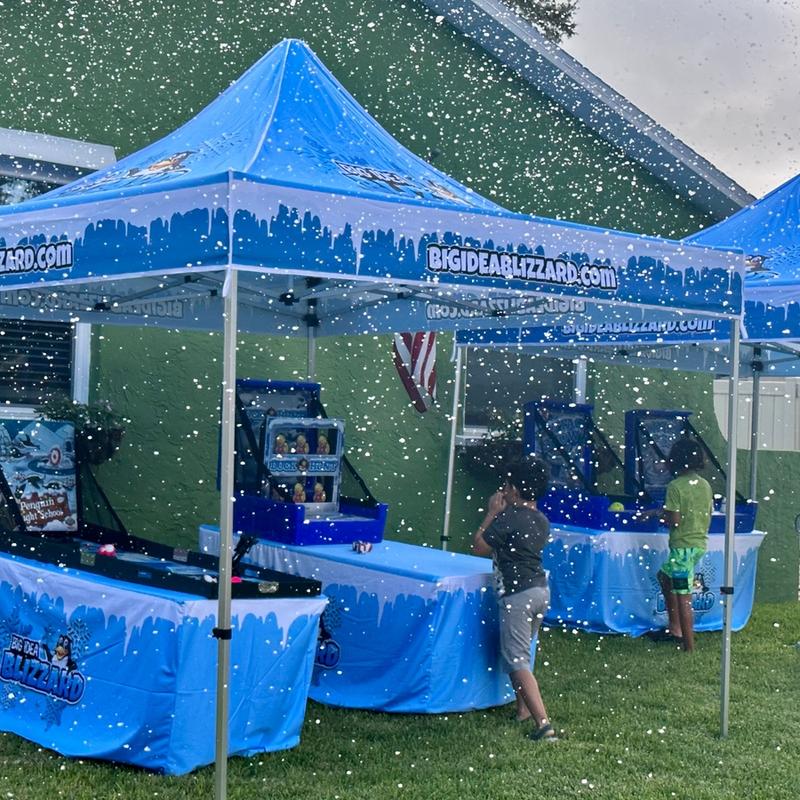 Two Big Idea Blizzard tents with winter games on a lawn, with snow falling over kids at play