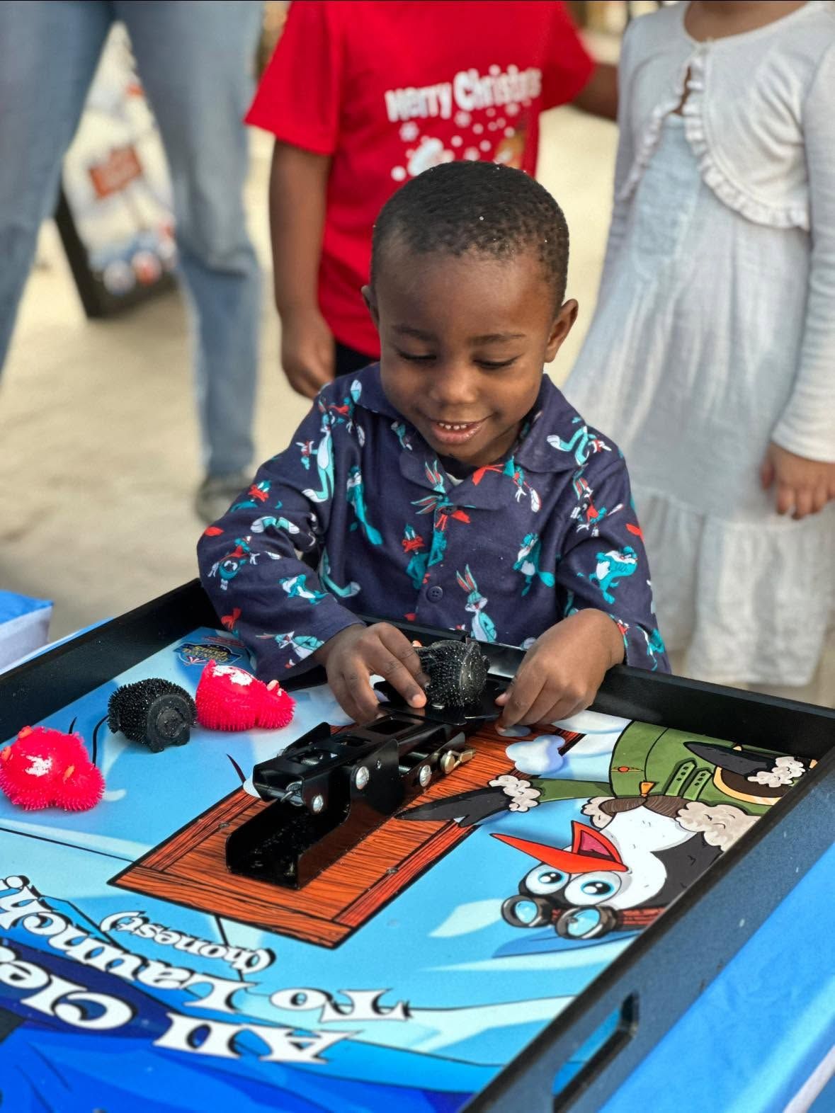 A toddler in a holiday shirt loads the Penguin Flight School launcher