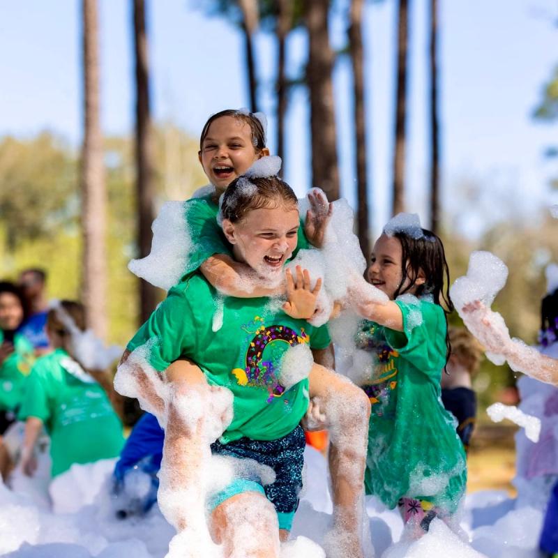end of the school year field day foam party, kids smiling and laughing