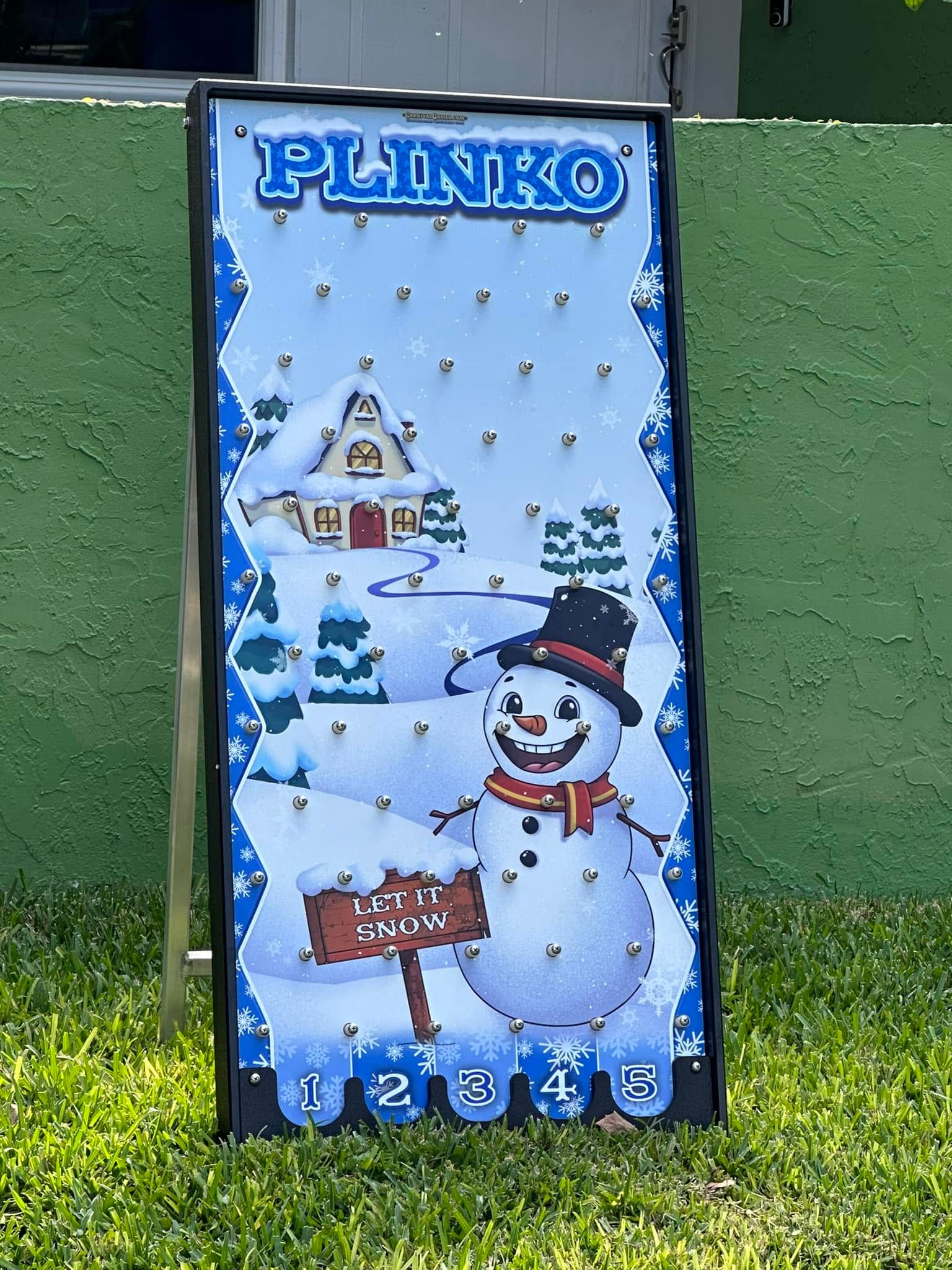 The Let It Snow Plinko board with its snowman scene, set up on the lawn