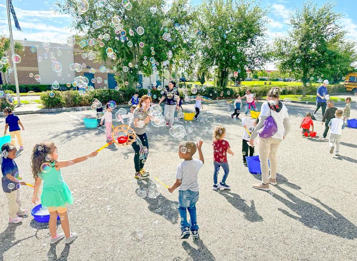 kids making bubbles from buckets on a paved schoolyard