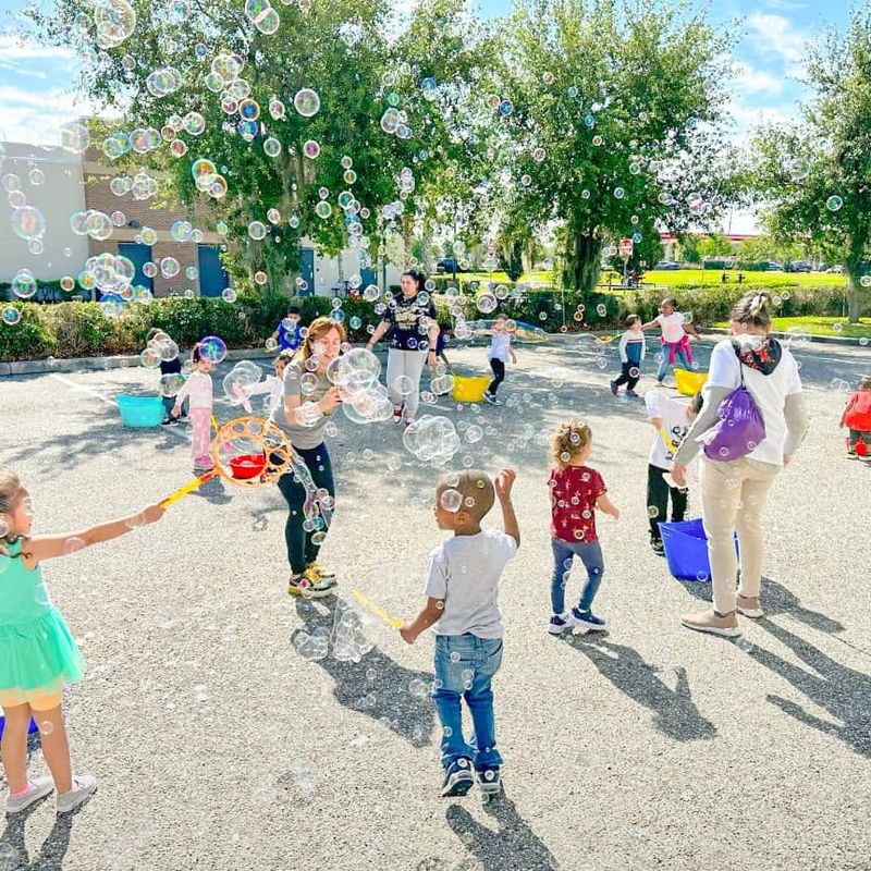 kids making bubbles from buckets on a paved schoolyard
