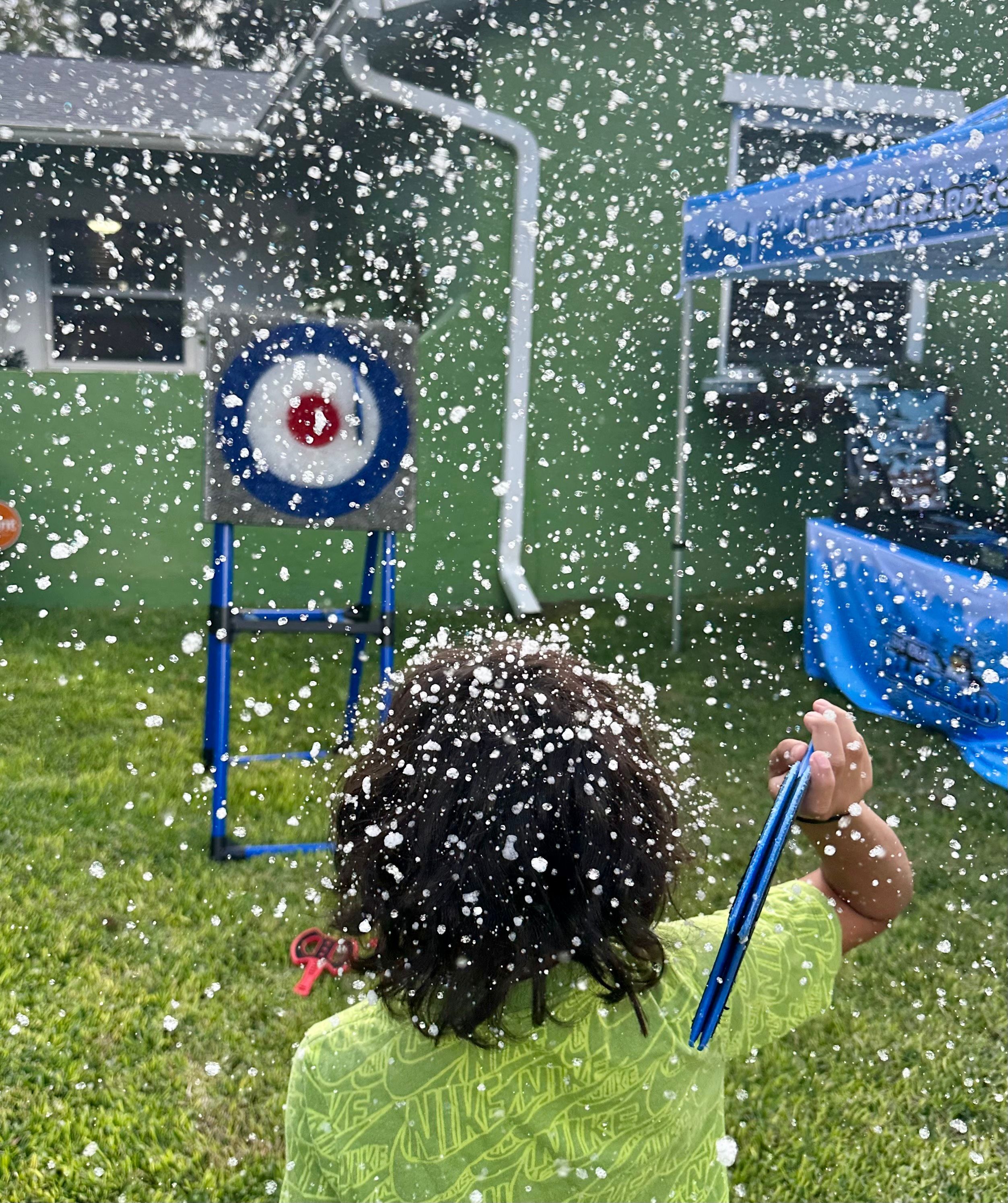 Snow covers the back of a boy's head as he faces the axe-throw target