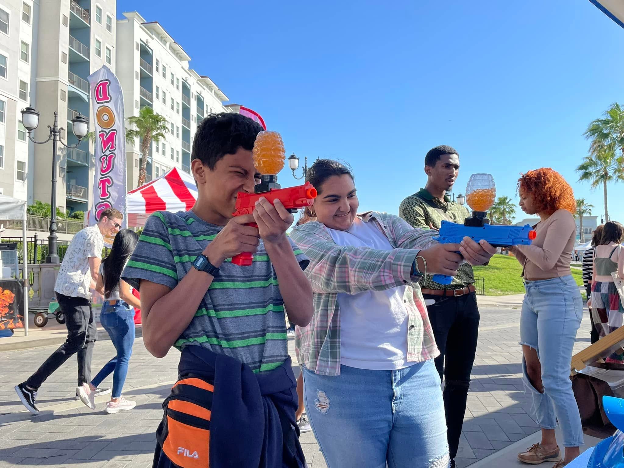 Festival guests take aim with gel blasters at a gellyball booth