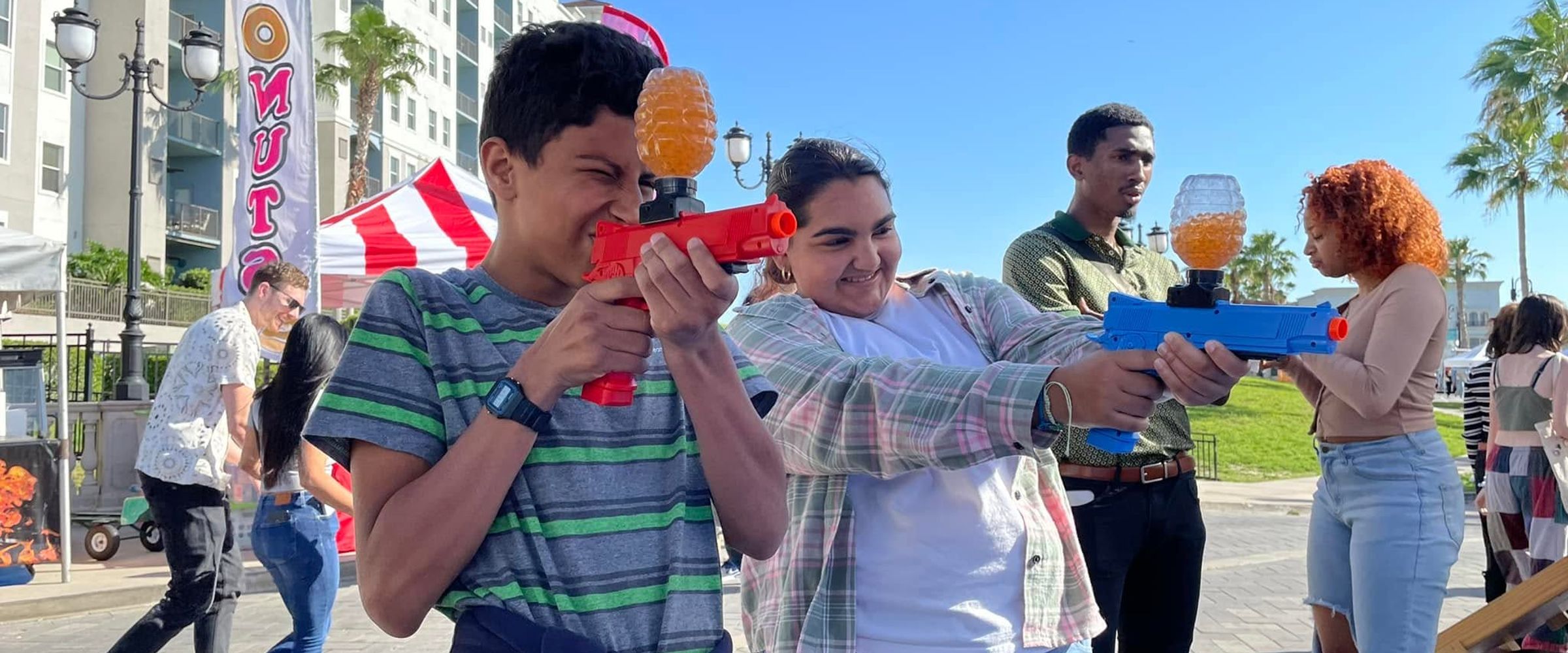 Festival guests take aim with gel blasters at a gellyball booth