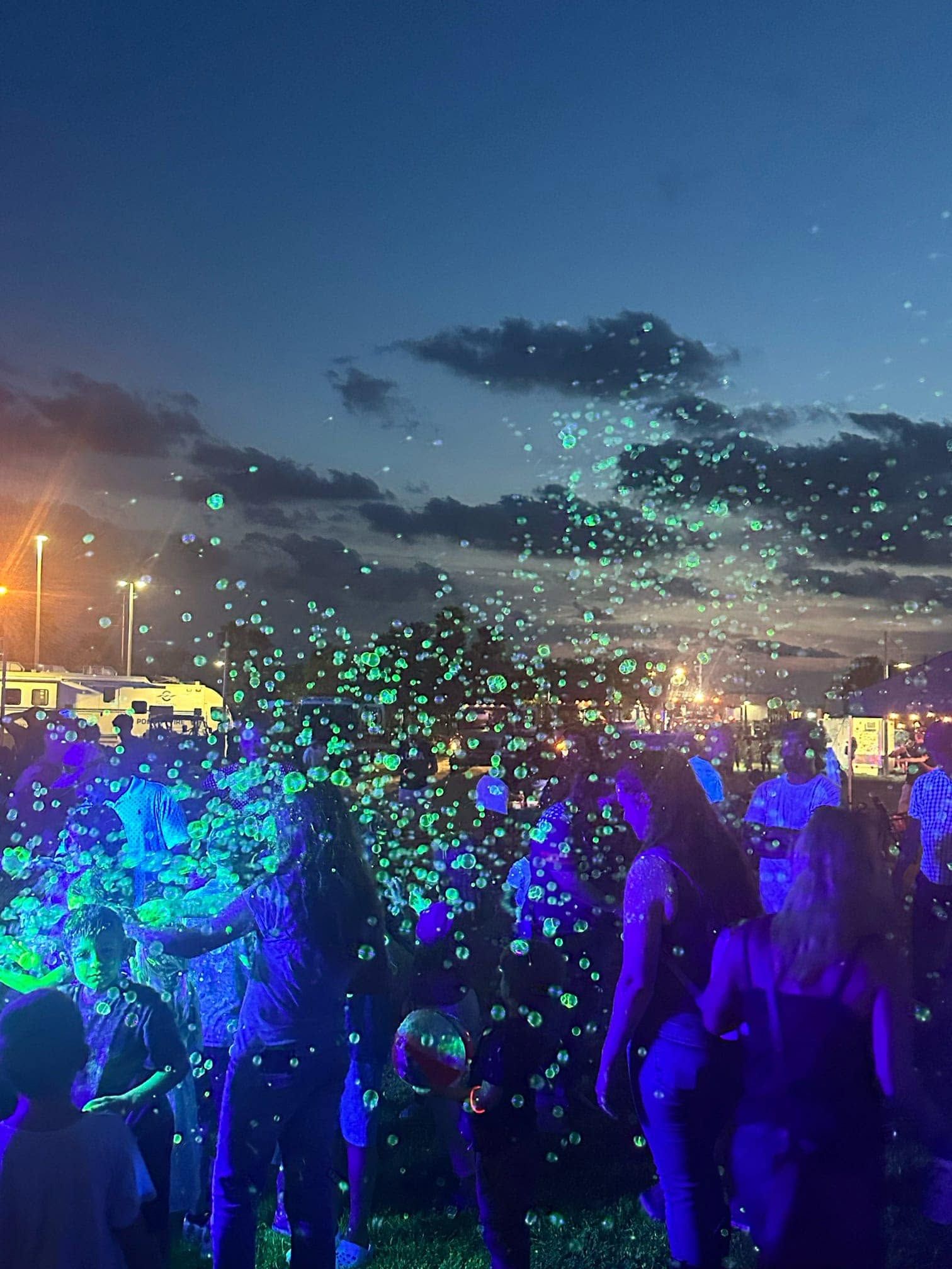 a night crowd under glowing bubbles at a community event