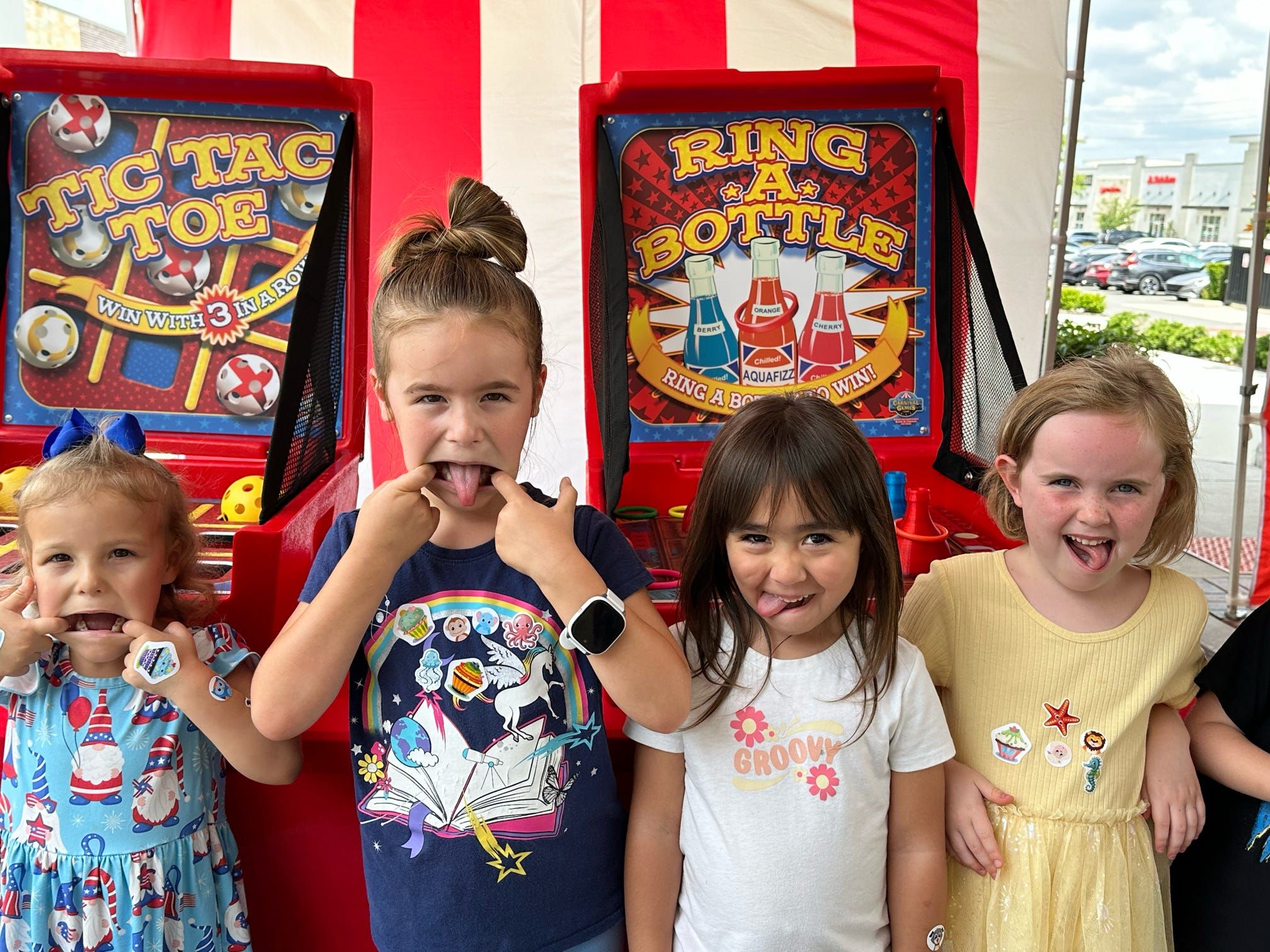 Kids smiling in front of several carnival games at a carnival event