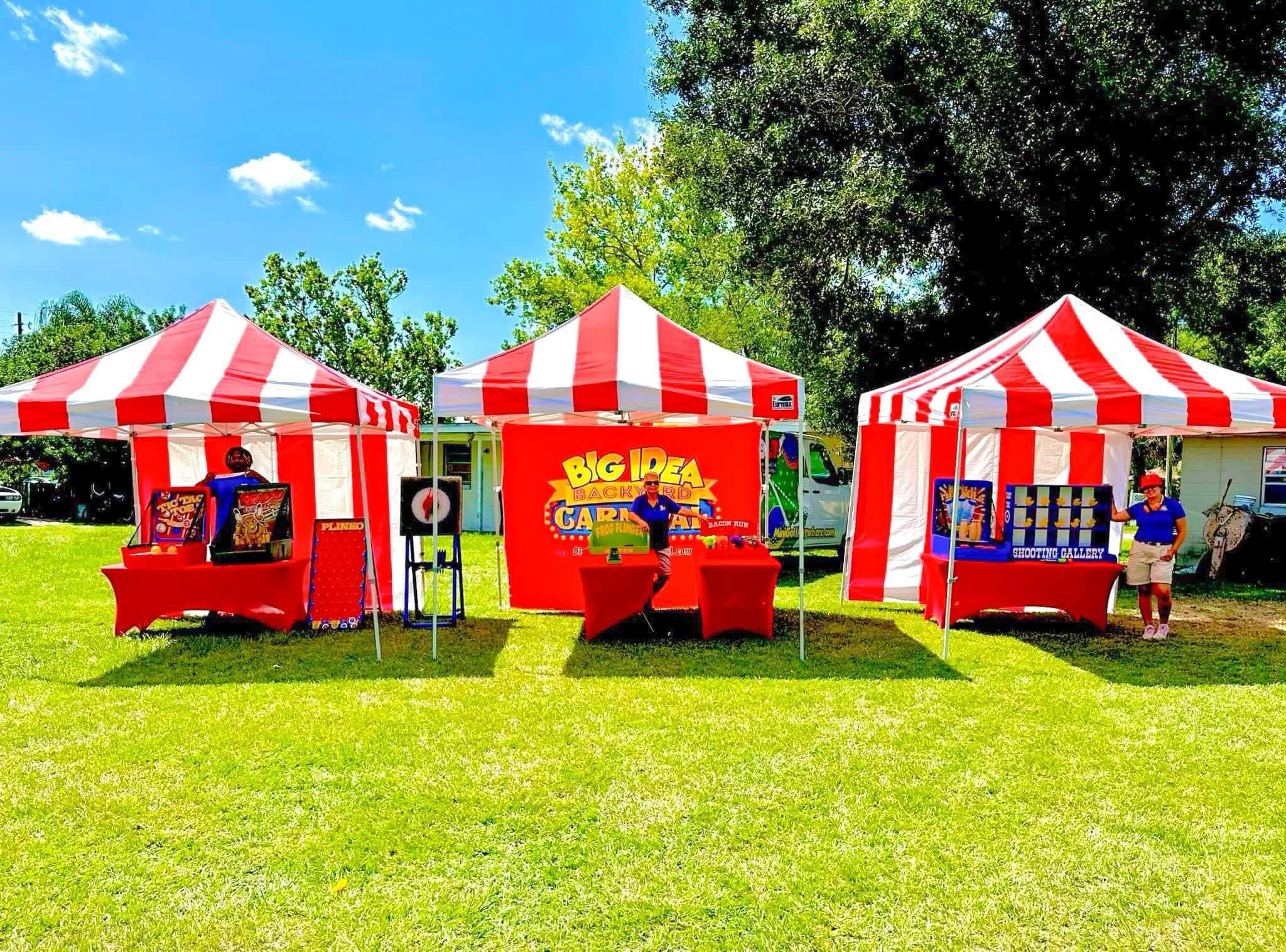 Three red and white striped tents setup with classic carnival games in preparation for a community festival.