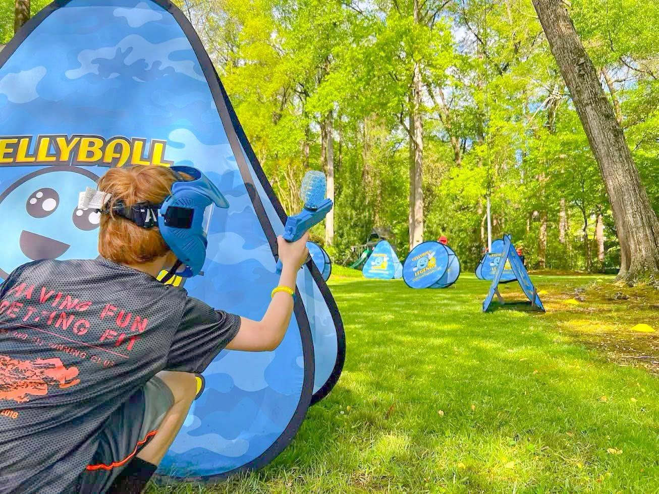 A player in a blue mask crouches behind a bunker, with more bunkers on the lawn behind