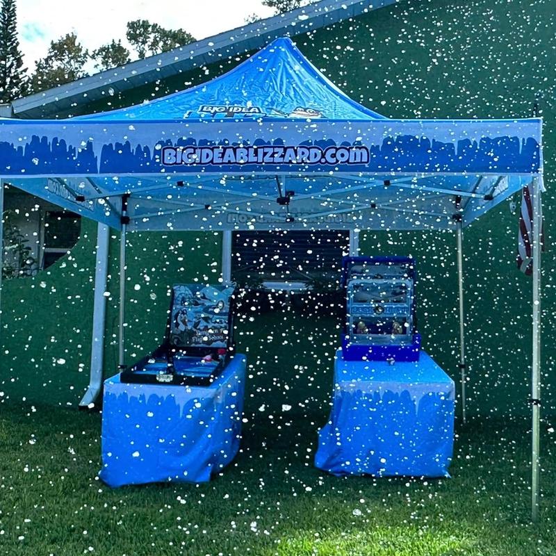 A Big Idea Blizzard tent over two game tables in heavy falling snow beside a house
