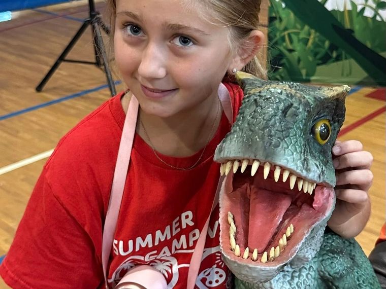 A girl hugs a lifelike baby T. rex