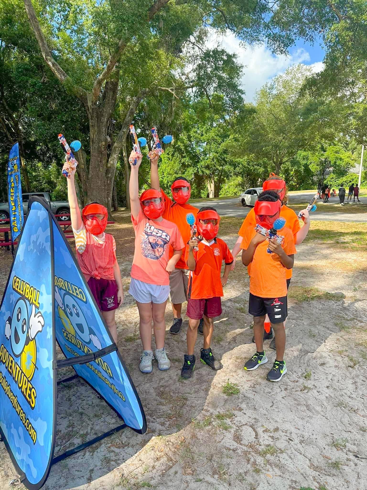 A group of kids in masks cheer with their gel blasters raised