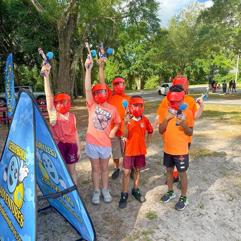 A group of kids in masks cheer with their gel blasters raised