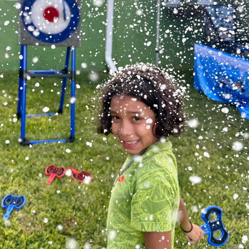 A boy with snow in his hair holds a soft throwing axe