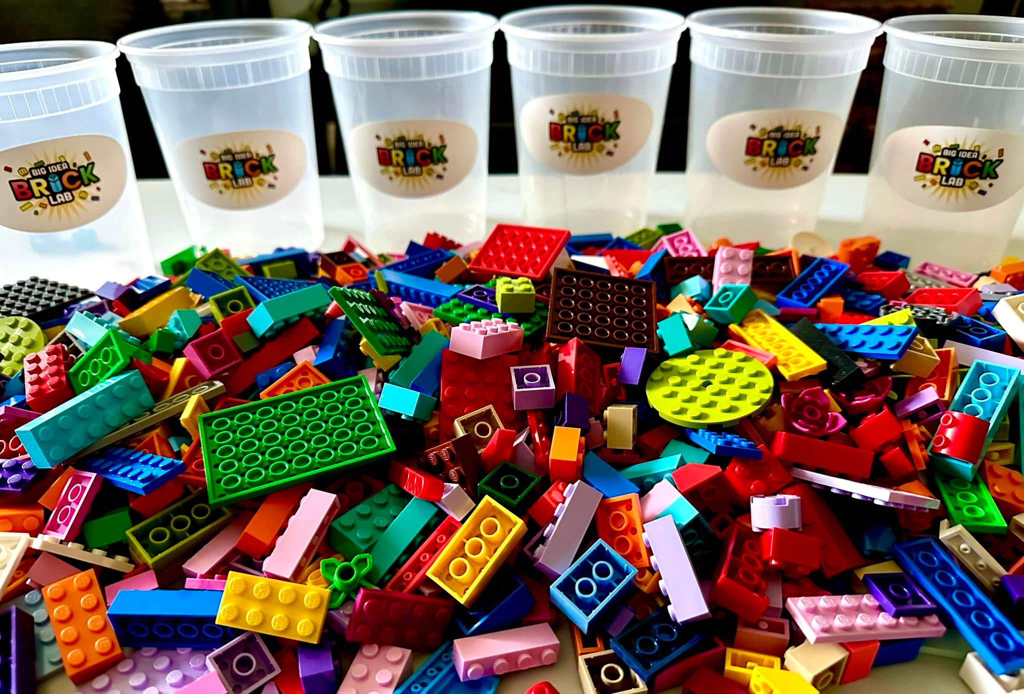 A heap of colorful building bricks in front of a row of Brick Lab cups
