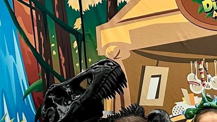 A tyrannosaurus skull cast and jungle backdrop on the Dinosaur Adventures set