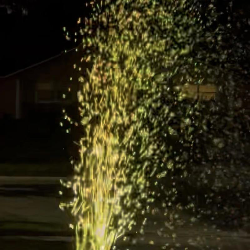a bubble machine throwing a column of bubbles into the air on a lawn at night