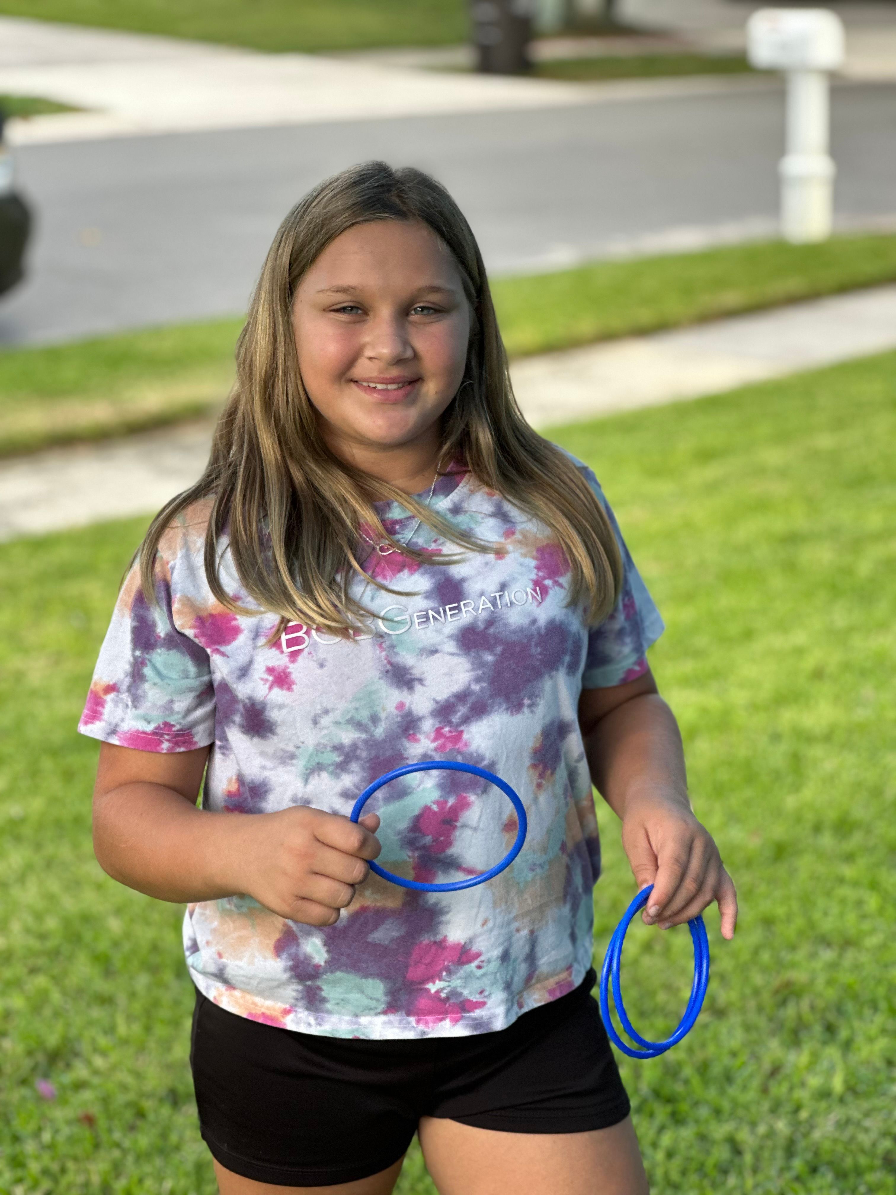A girl holds a handful of toss rings, ready to play