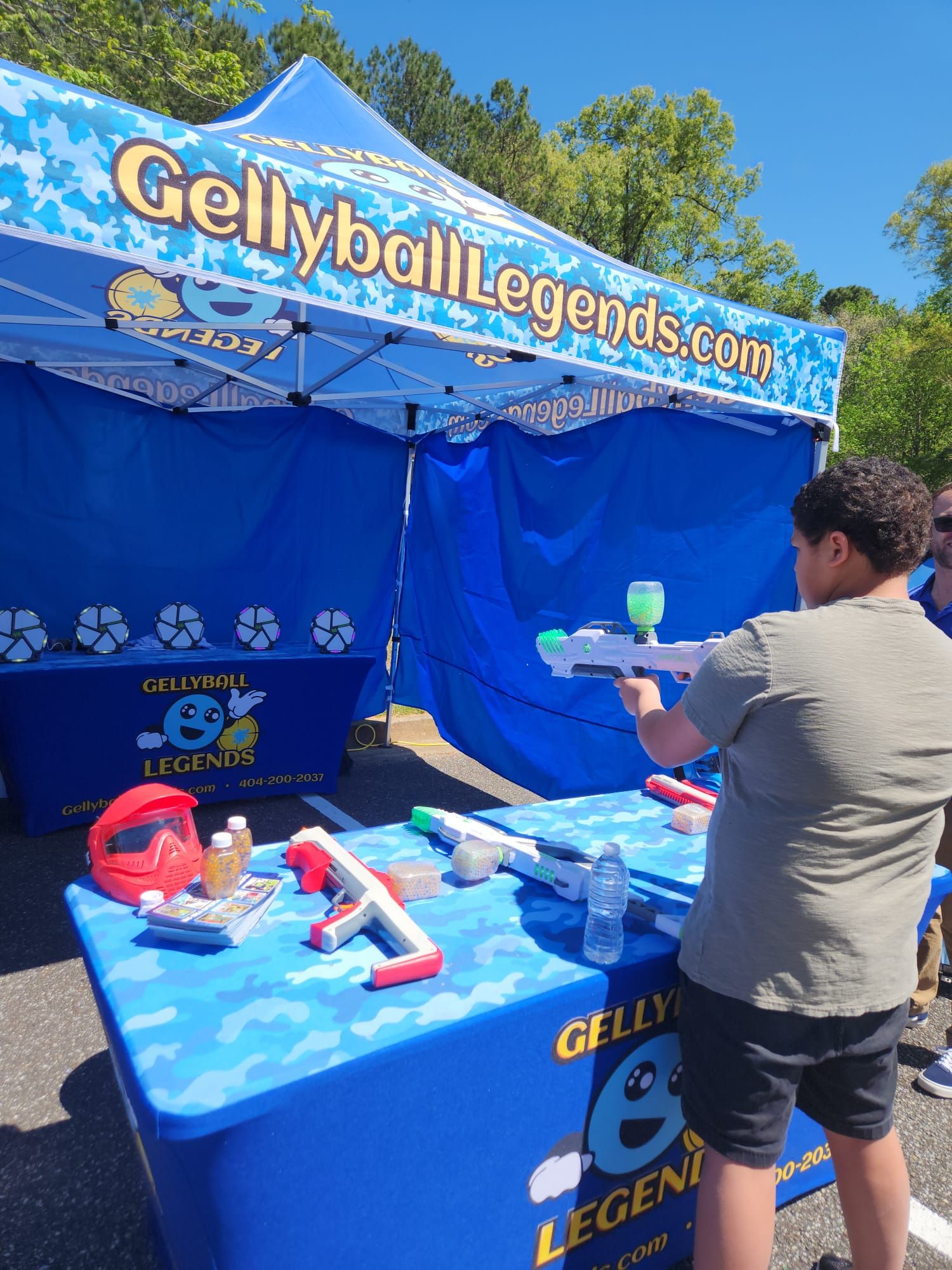 A boy takes aim at a row of light-up digital targets inside a blue gellyball tent