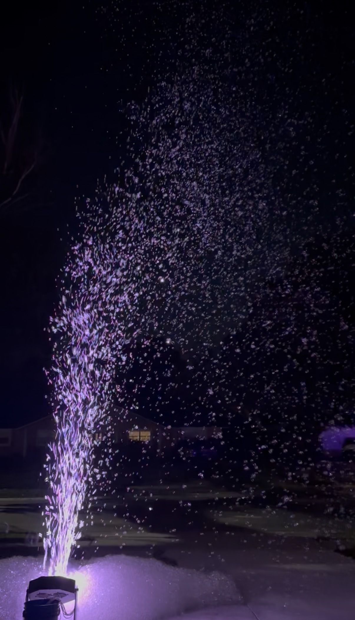 a bubble machine lit from below sending bubbles skyward at night