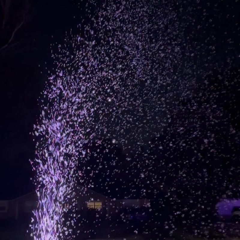 a bubble machine lit from below sending bubbles skyward at night