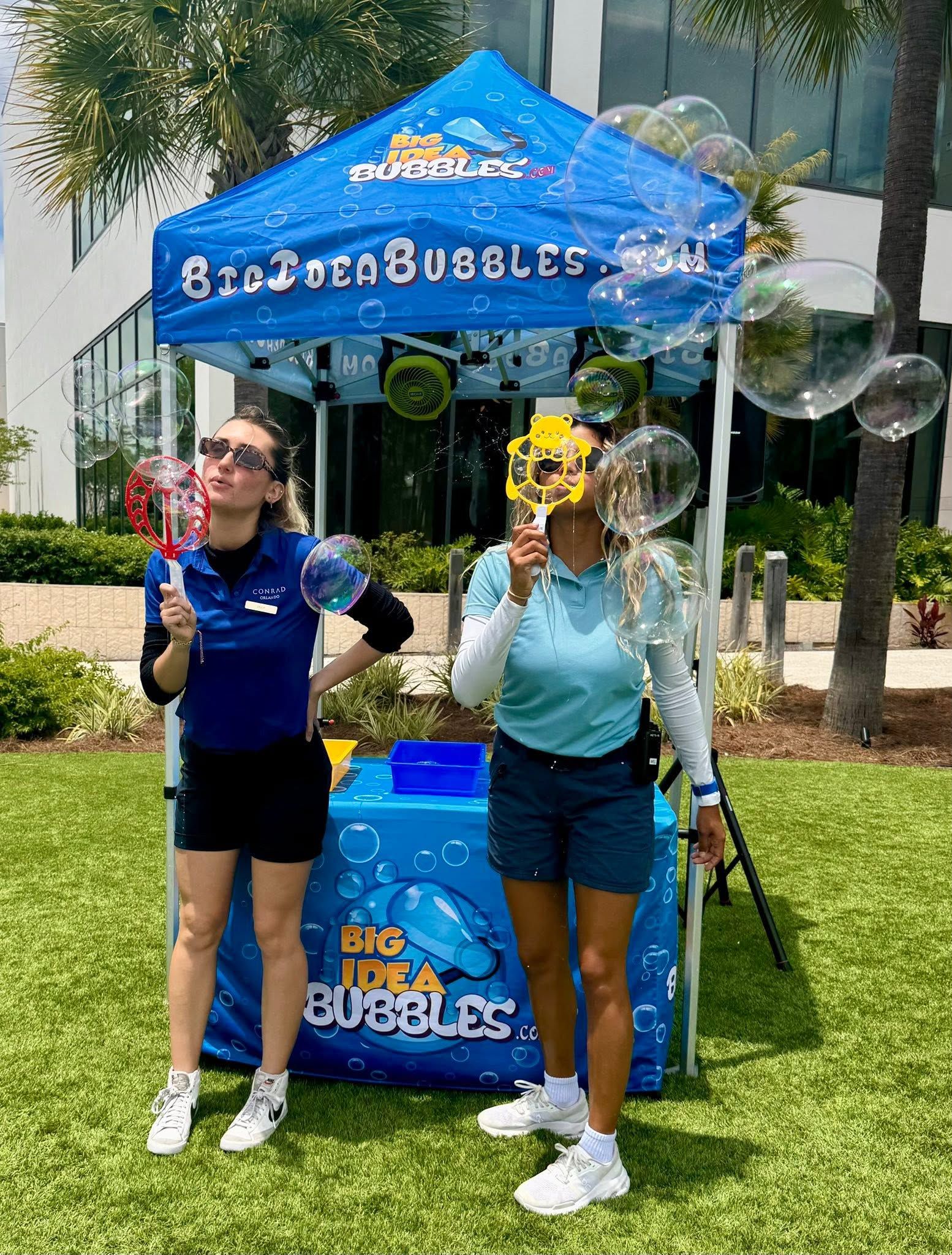 two hosts making giant bubbles in front of a branded Big Idea Bubbles tent