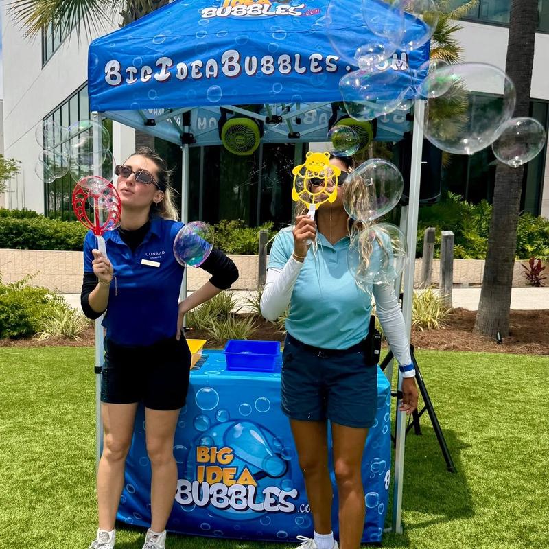 two hosts making giant bubbles in front of a branded Big Idea Bubbles tent