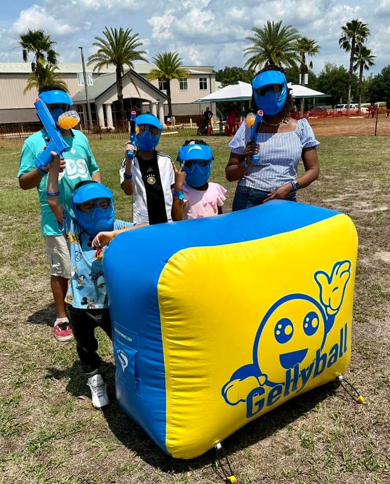 Kids and a parent in masks gather behind an inflatable bunker