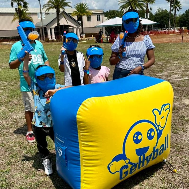 Kids and a parent in masks gather behind an inflatable bunker