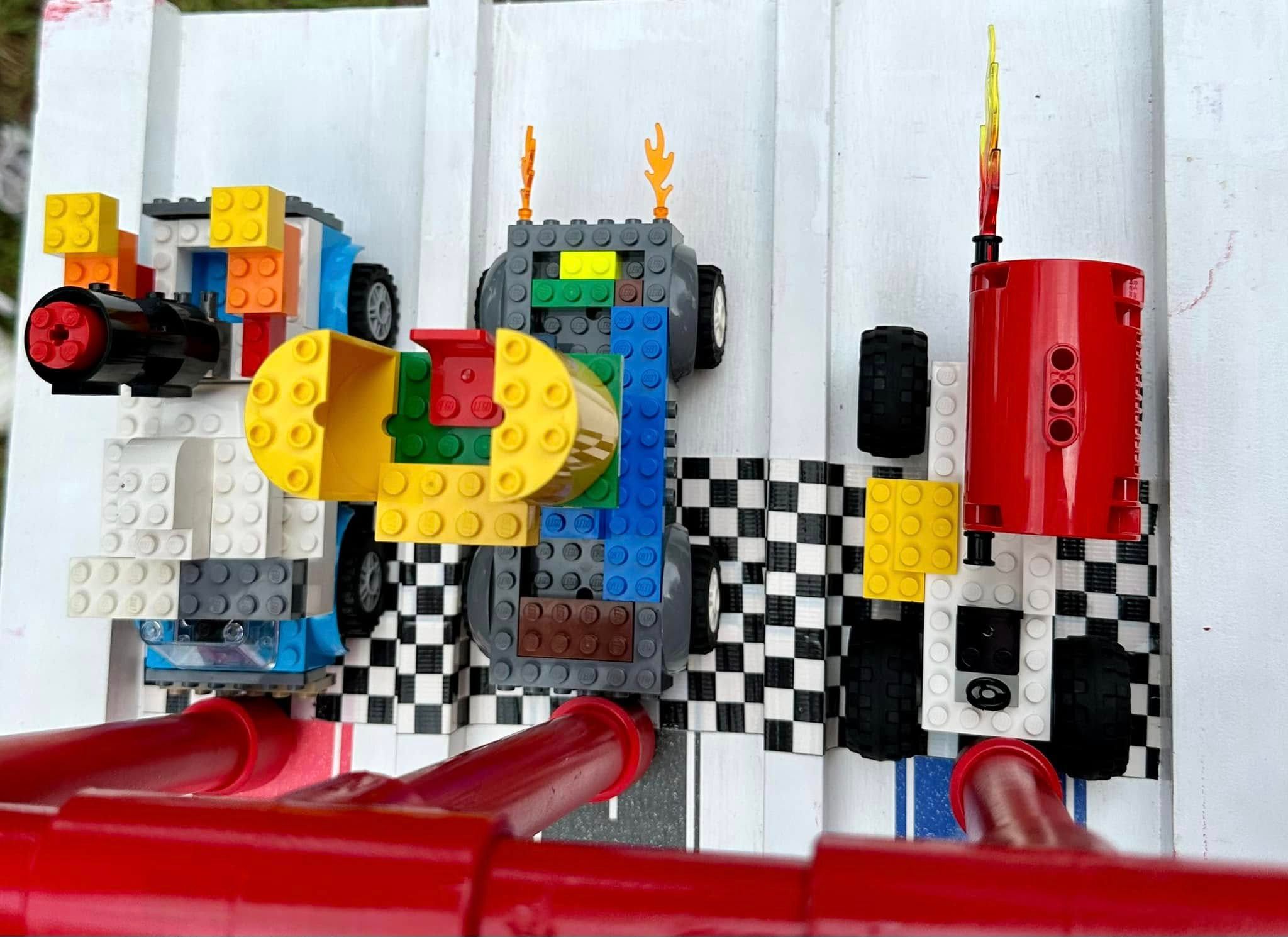 Three kid-built brick cars, one with flame pieces, lined up on the checkered start of the Derby ramp