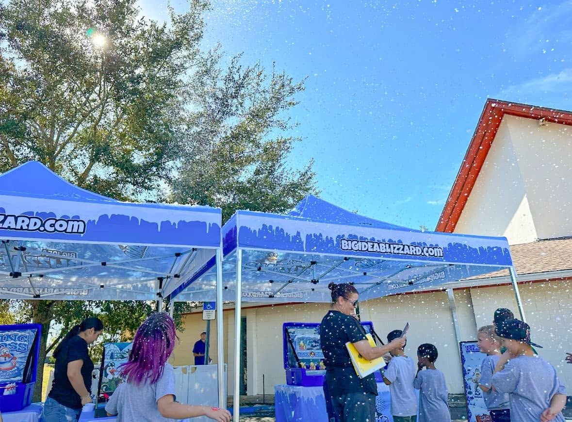 Two Blizzard tents with winter games under a blue sky as a group of kids plays