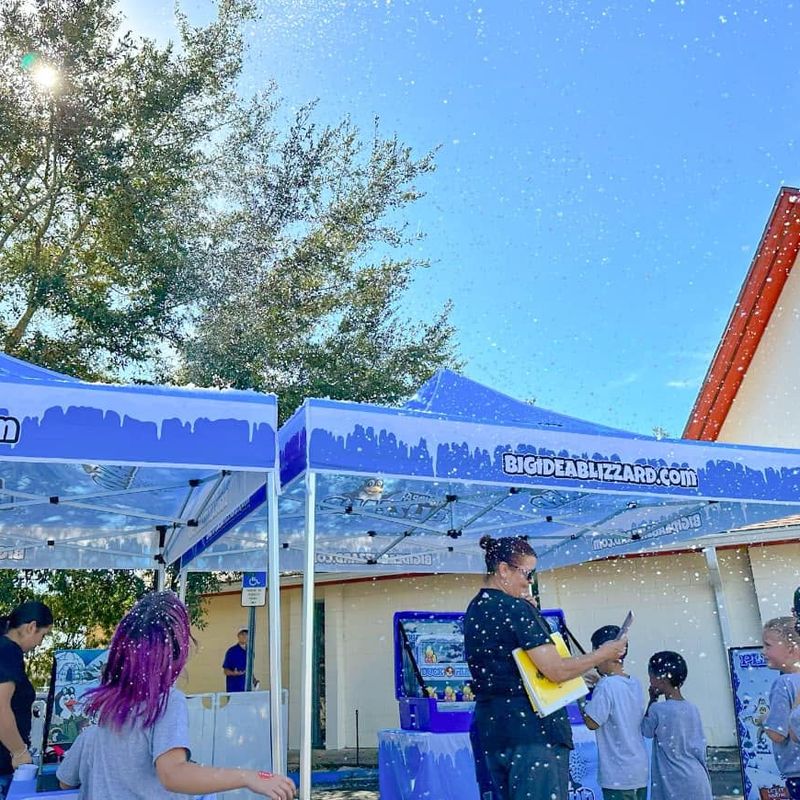 Two Blizzard tents with winter games under a blue sky as a group of kids plays