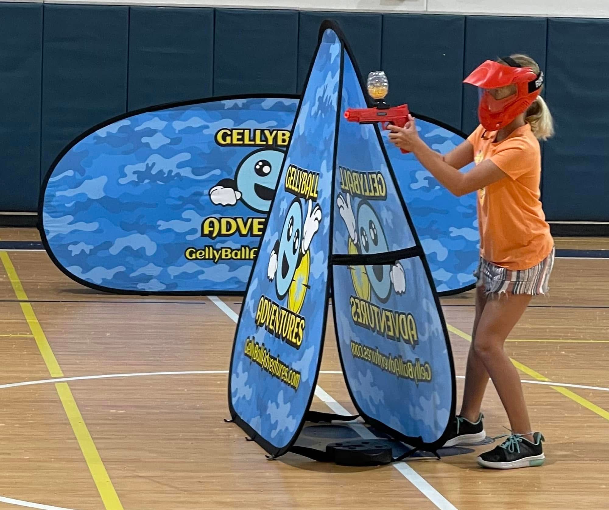 A student plays gellyball between pop-up bunkers on a school gym floor
