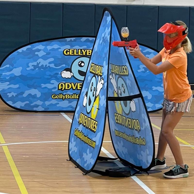 A student plays gellyball between pop-up bunkers on a school gym floor