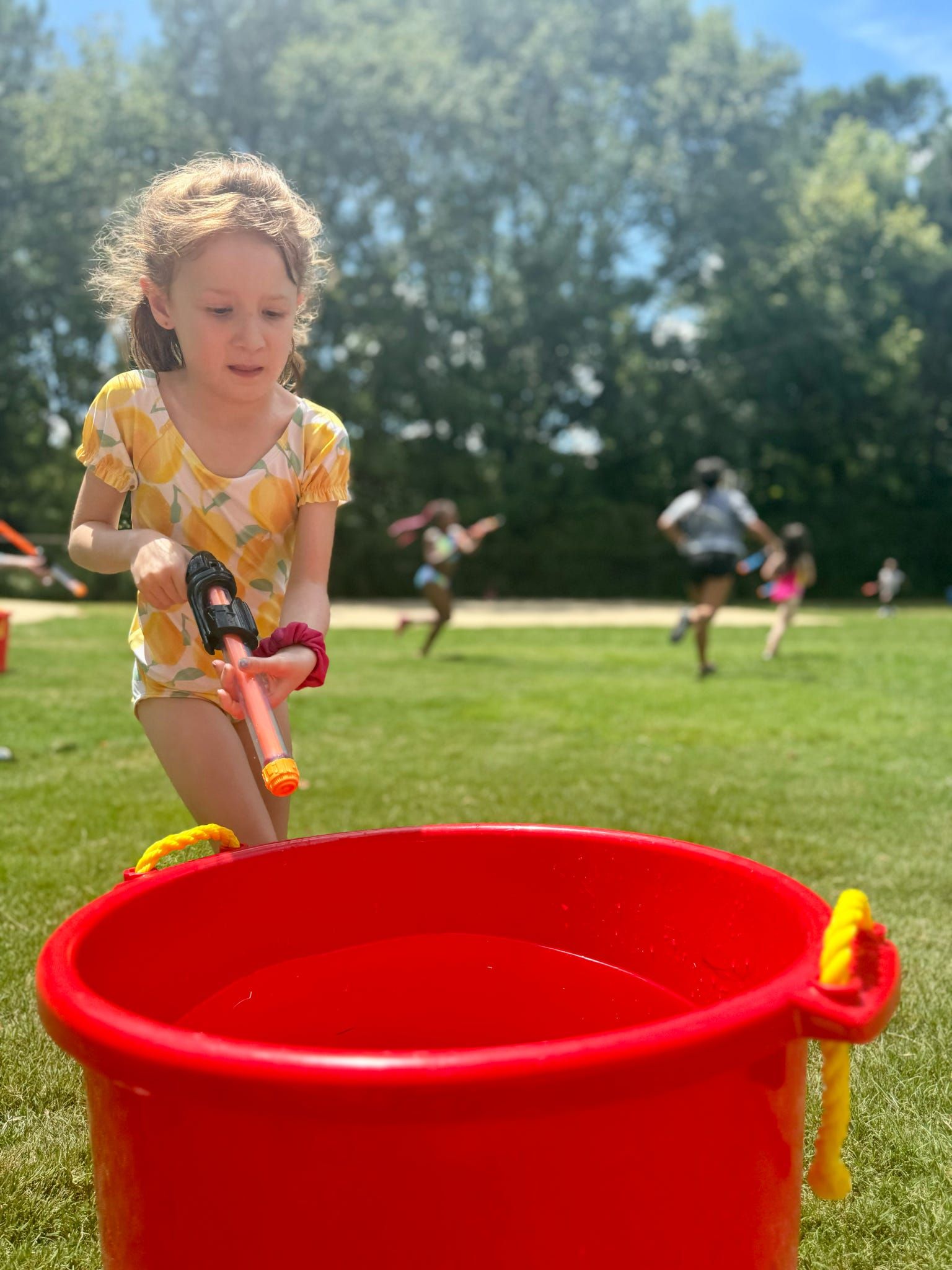 A girl fills her blaster at a red refill tank