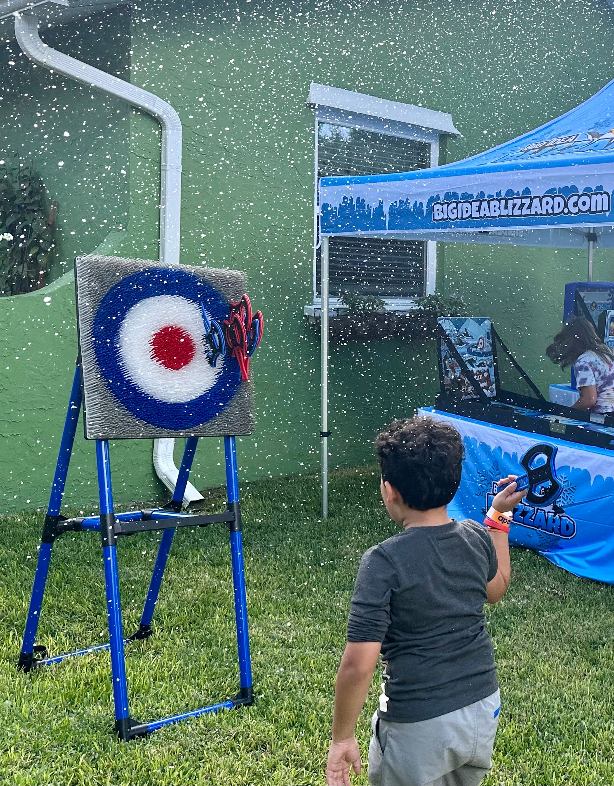 A boy throws a soft axe at the target while snow falls