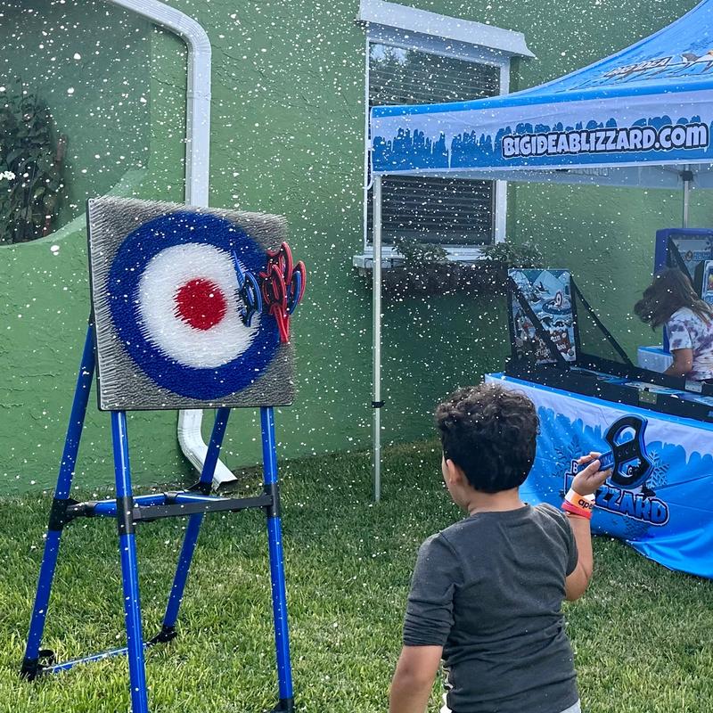 A boy throws a soft axe at the target while snow falls