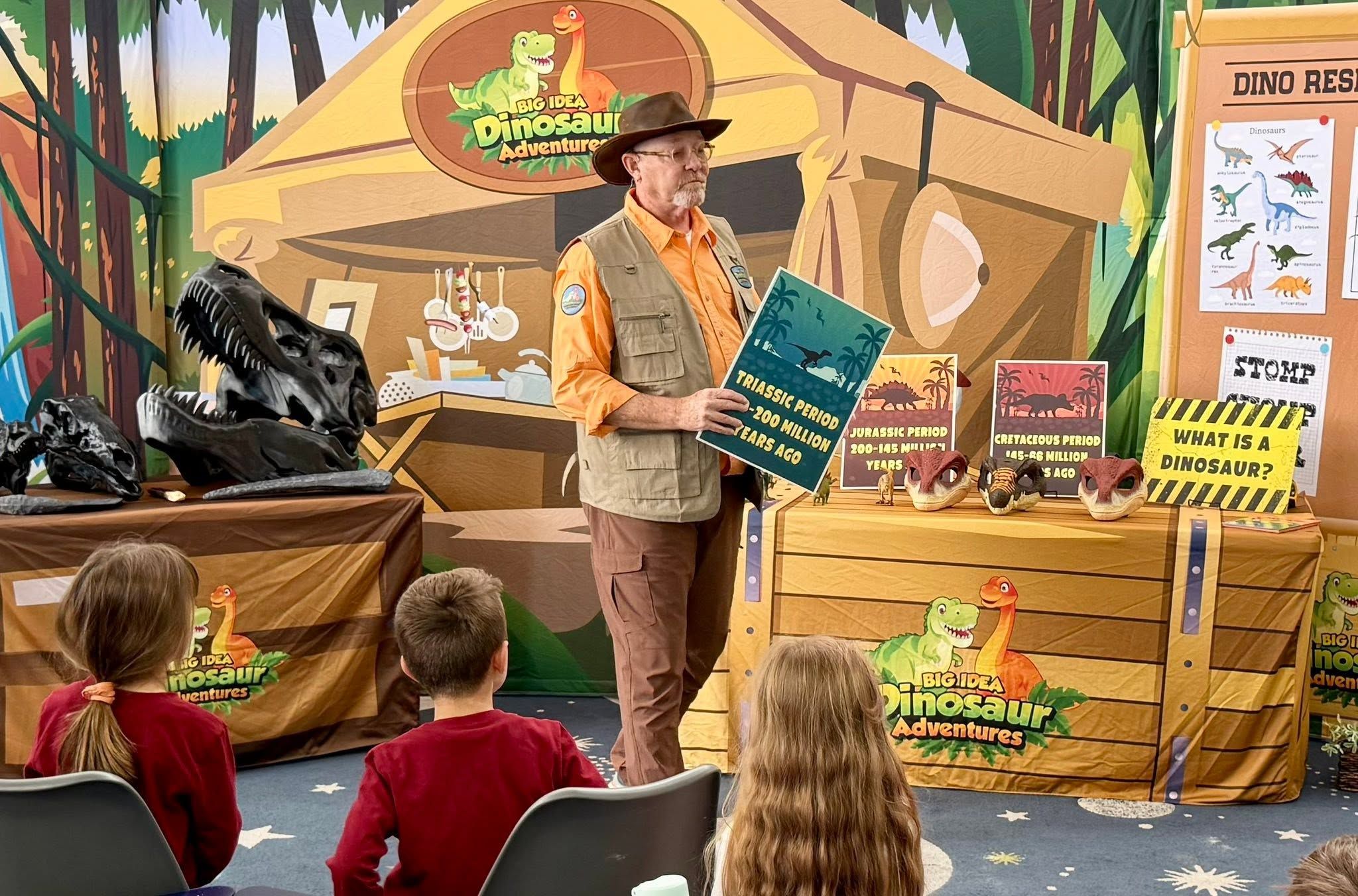 Performers on stage during a dinosaur school assembly for elementary students