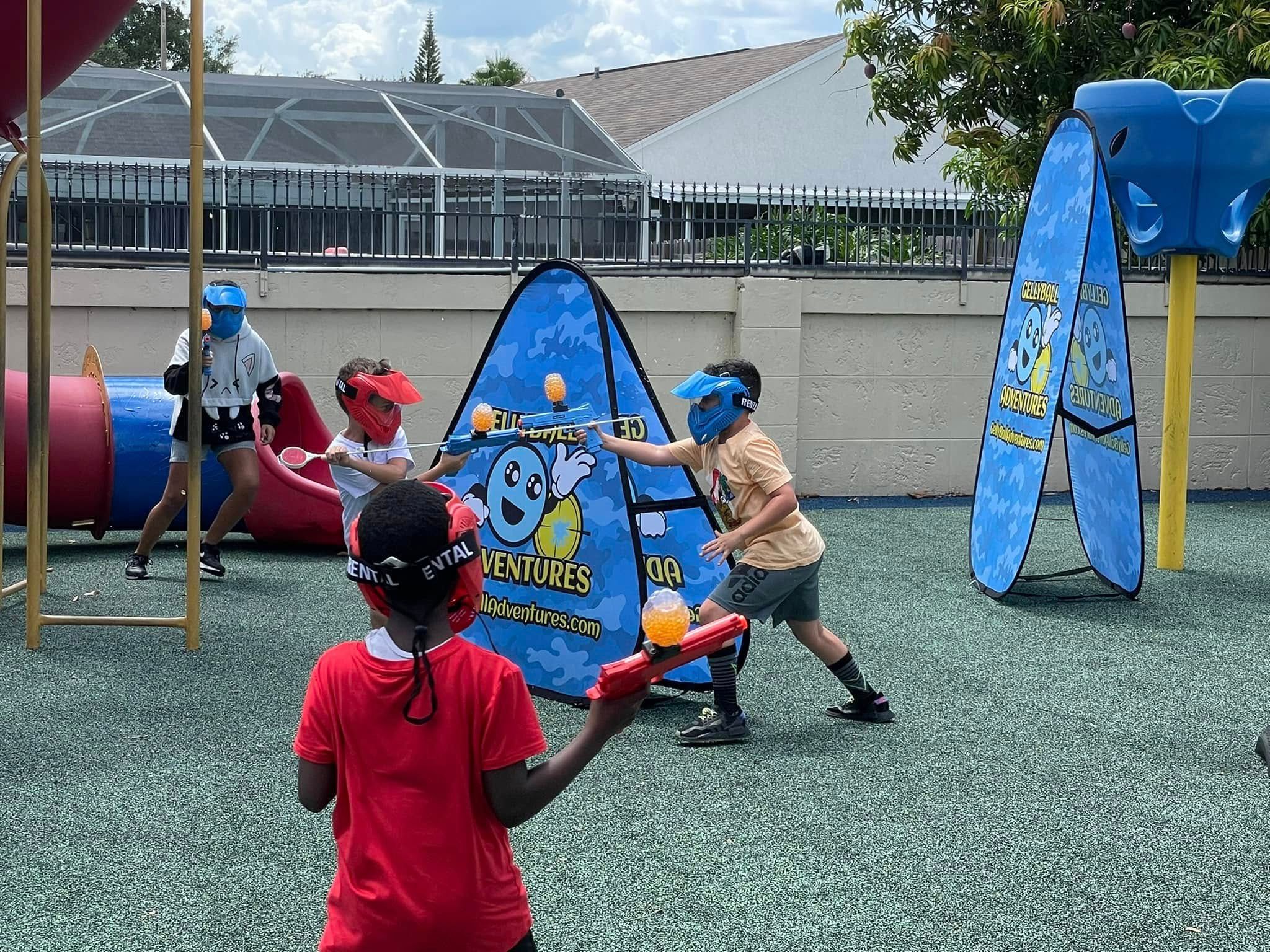 Children play gellyball around pop-up bunkers on a playground